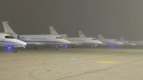 Private jets lined up apron tarmac parking position foggy night scene reflects Vidéo 300346529