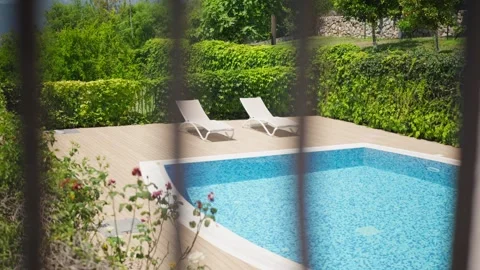 Private pool with mosaic tiling and lounge chairs behind fence Stock Footage 327013658