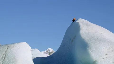 Pro climber reaching summit of huge frozen formation on Alaskan glacier Stock Footage 129111994