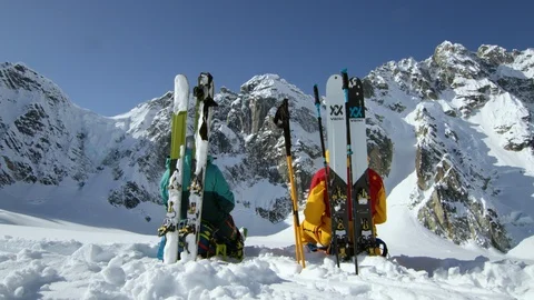 Pro freeride skiers resting on ground, pointing towards snowy mountains, Alaska Video stock 129126907