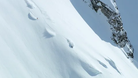 Pro freeride skiers skiing down from big mountain in remote area, Alaska Stock Footage 129101707