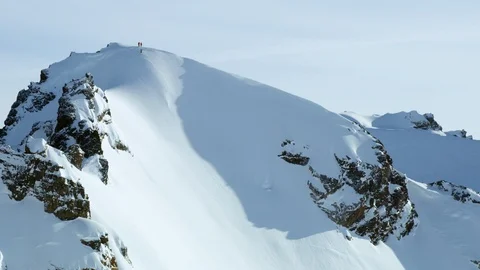 Pro freeride skiers skiing down from big snowy mountain on sunny day, Cordova Stock Footage 129101796