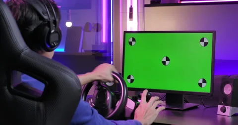 Pro gamer in simulator steering wheel playing with green chroma key monitor. Video stock 134591564