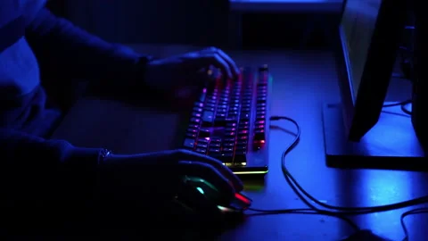 Pro gamer sitting at the table in dark blue illuminated office and playing Stock-Footage 146858080