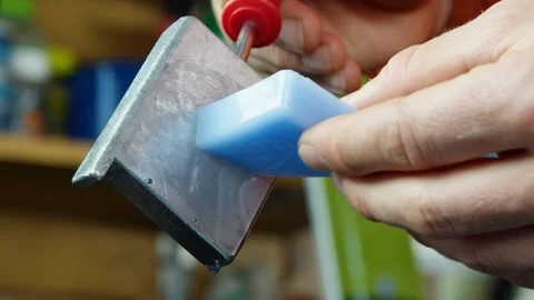 Pro hiker using melting tool to melt chunk of blue paraffin wax for his skis Stock Footage 129126925