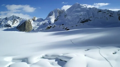 Pro hikers walking in clear snow near mountains covered in snow, Alaska Stock Footage 129126135