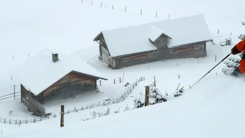 Pro skier freeriding down into valley, cabins in background, Switzerland Stock Footage 129084762