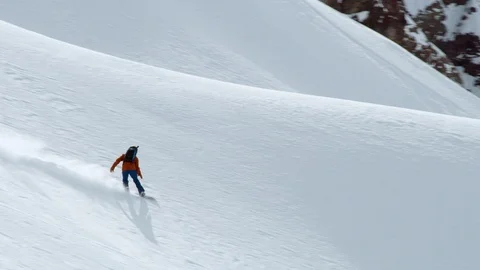 Pro snowboarder balancing on steep slope, riding down on ungroomed surface Stock Footage 121597270