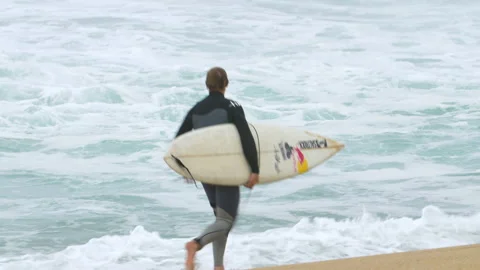 Pro surfer Andrew Cotton jumping on surfboard and paddling to get to ocean waves Stock Footage 155999945