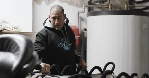 Pro surfer David Langer adjusting jet ski and surfing board in garage Stock Footage 160584686