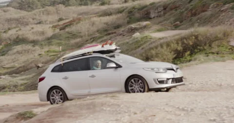Pro surfer David Langer driving car on rocky road during sunny day Stock Footage 164321666