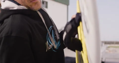 Pro surfer David Langer securing surfboard on jet ski to go riding big waves Stock Footage 163077574