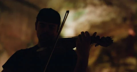 Pro surfer Nuno Santos playing violin inside underground stalactite caves Stock Footage 155257689