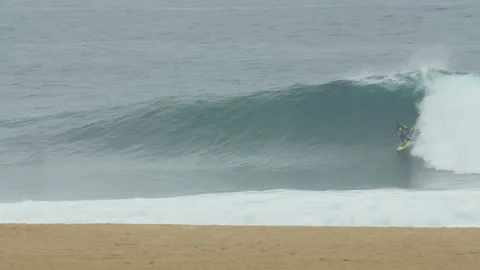 Pro surfer riding big wave in ocean near beach during day time Stock Footage 155596293