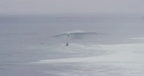 Pro surfer riding on ocean waves near jet ski driver during cloudy day Video stock 156007788