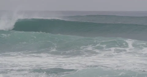 Pro surfers being dragged by wild ocean wave during cloudy day, Nazare Stock Footage 156007598