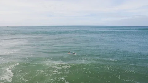 Pro surfers floating o surfboards in wavy ocean on sunny day in Nazare Stock Footage 157133623
