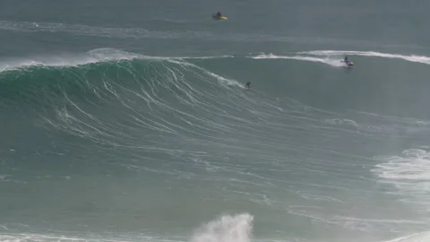 Pro surfers riding big waves on surfboards and jet skis in wild ocean, Nazare Stock Footage 157701341