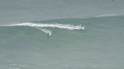 Pro surfers riding wild waves in ocean on jet skis and surfboards on sunny day Stock Footage 157698785