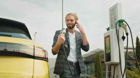 Problem with charging an electric car. Emotional talking by the phone. Young Stock Footage 235361924