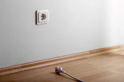 Problem to connect. White power socket on beige wall at low height from the f Stock Photos