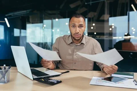 Problem with documents at work. Upset young African-American businessman working Stock Photos