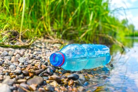 The problem of plastic pollution. A plastic bottle thrown away by the river Stock Photos