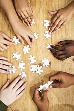 Problem solving like pros. Shot of a group of people building a puzzle togeth Stock Photos
