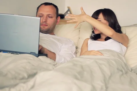 Problems in bed, woman screaming at man while he works on laptop NTSC Stock Footage 4982875