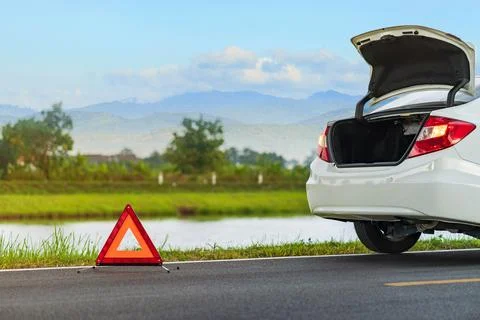 Problems car and a red triangle warning sign on the road Stock Photos