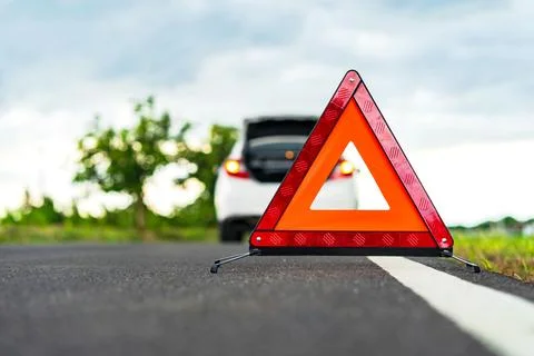 Problems car and a red triangle warning sign on the road Stock Photos