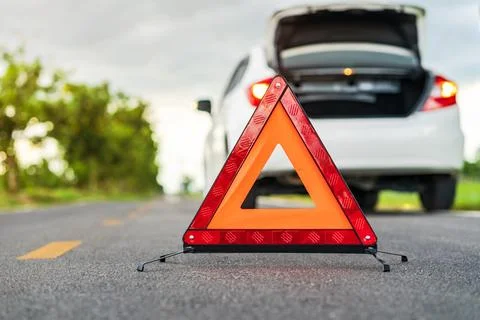 Problems car and a red triangle warning sign on the road Stock Photos