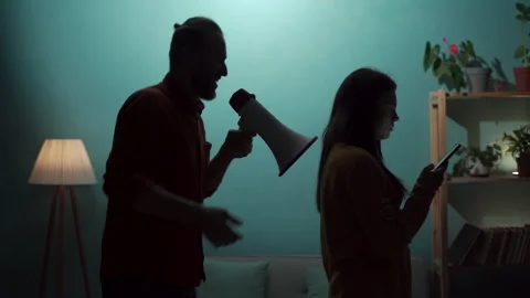 Problems in relationships. A young angry man shouting into a loudspeaker at his Stock Footage 254404434