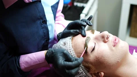 Procedure of eyebrow microblading. A master in black gloves is doing a blending Stock Footage 199962599
