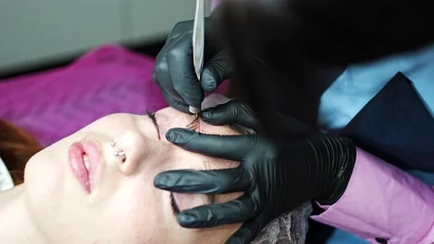 Procedure of eyebrow microblading. A master in black gloves is doing a blending Stock Footage 199963325