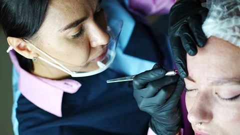 Procedure of eyebrow microblading. A master in black gloves is doing a blending Stock Footage 200831875