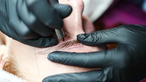 Procedure of eyebrow microblading. A master in black gloves is doing a blending Stock Footage 200832293