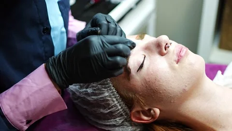 Procedure of eyebrow microblading. A master in black gloves is doing a blending Stock Footage 201080736