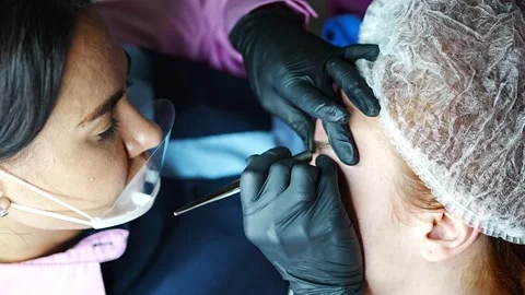 Procedure of eyebrow microblading. A master in black gloves is doing a blending Stock Footage 201473931