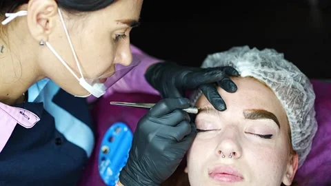 Procedure of eyebrow microblading. A master in black gloves is doing a blending Stock Footage 201474042