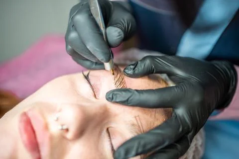 Procedure of eyebrow microblading. A master in black gloves is doing a blending Foto stock
