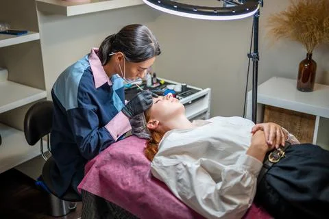 Procedure of eyebrow microblading. A master in black gloves is doing a blending Stock Photos