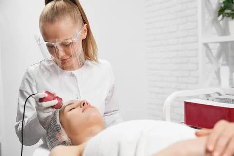 Procedure for face with special machine for young woman. Stock Photos