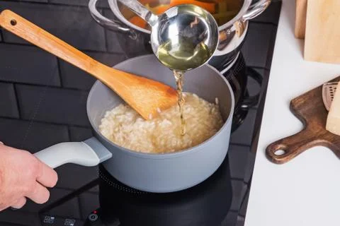 Process of adding broth while cooking risotto Stock Photos