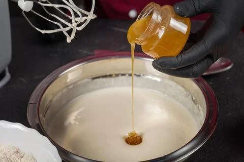 Process of adding honey to meringue Foto stock