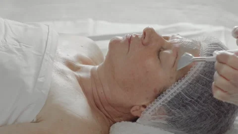 The process of applying an alginate mask to the face of an elderly woman in a Stock Footage 337123266