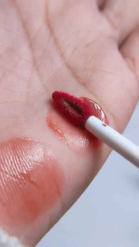 Process of applying lip tint color on palm. Vertical close up capture. Suit.. Видео 340970999