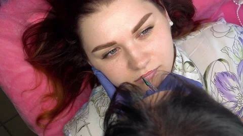 Process of applying permanent makeup tattoo of red on lips woman in beautician Stock Footage 168530569