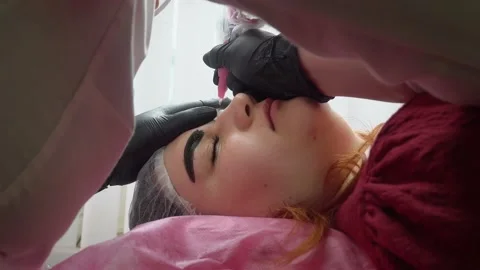 Process of applying permanent makeup tattoo of brown on eyebrows woman in Stock Footage 169110758