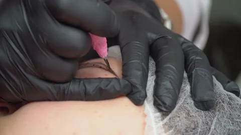 Process of applying permanent makeup tattoo of brown on eyebrows woman in Stock Footage 186511644
